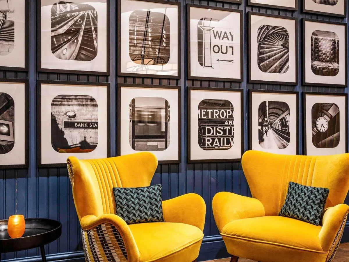 two yellow chairs in a room with pictures on the wall at ibis Styles London Gloucester Road in London