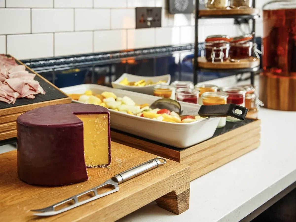 a cutting board with a cake and a plate of food at ibis Styles London Gloucester Road in London